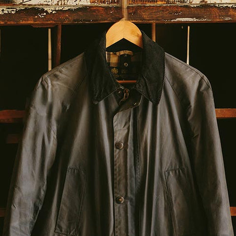 A Barbour wax jacket hanging up on a coat hanger