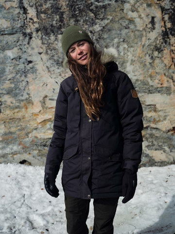 A woman standing in the mountains wearing a Fjallraven coat